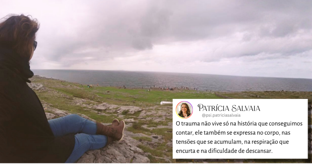 Mulher sentada em penhasco nos Cliffs of Moher, observando o mar ao longe sob vento forte e clima frio.