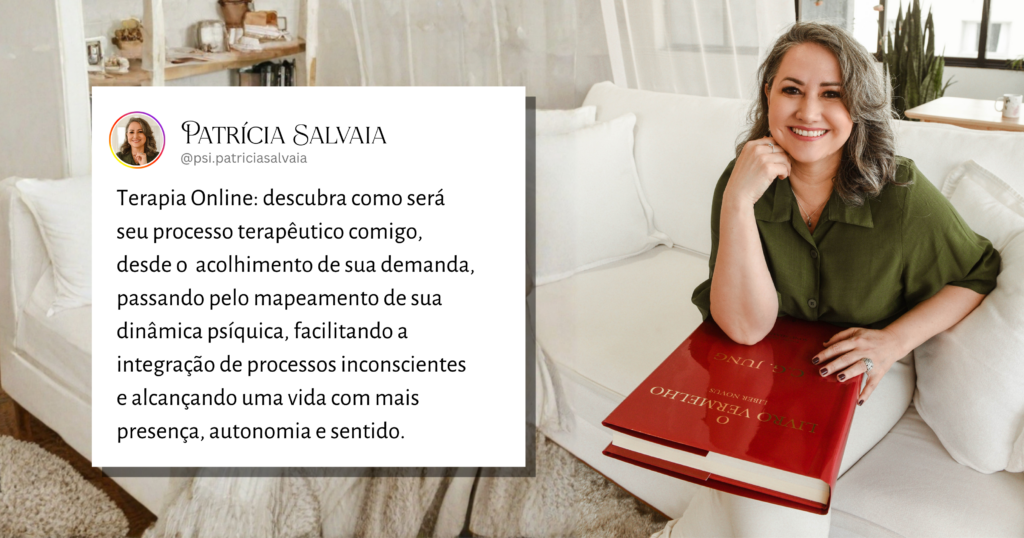 Psicóloga junguiana brasileira sentada em um sofá confortável, segurando o Livro Vermelho de Jung no colo e olhando para a câmera com uma expressão acolhedora e receptiva.